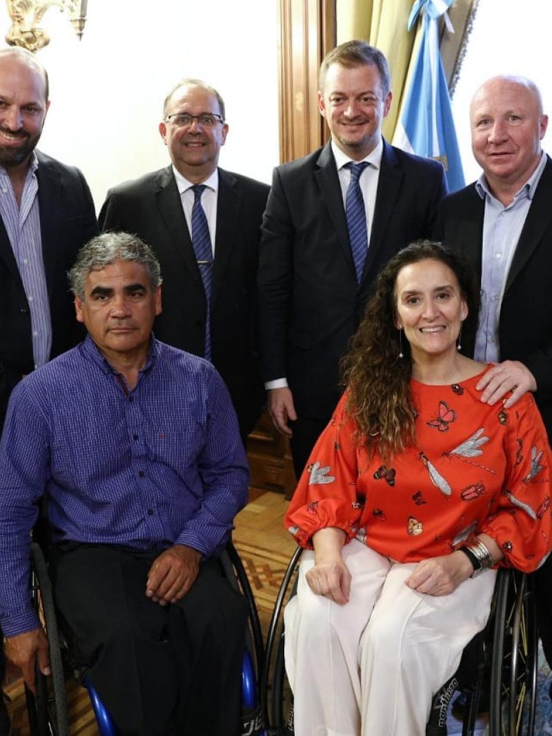 a group of people with Andrew Parsons at the centre in an official flag room