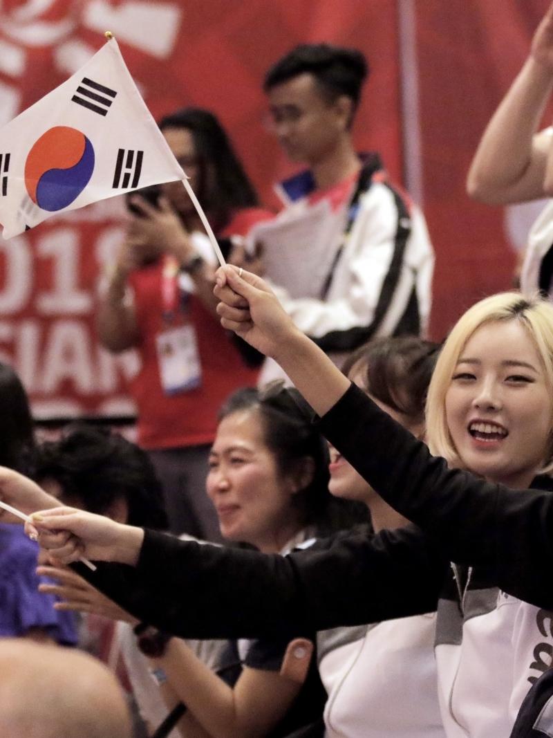 a group of men and women waving South Korean flags