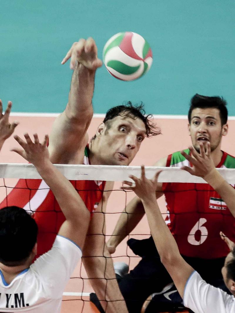 male sitting volleyball player Morteza Mehrzadselakjani blocks a ball over the net