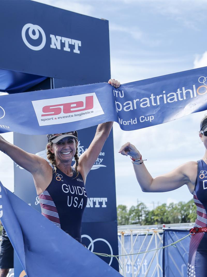 female Para triathlete Amy Dixon and her guide cross the finish line