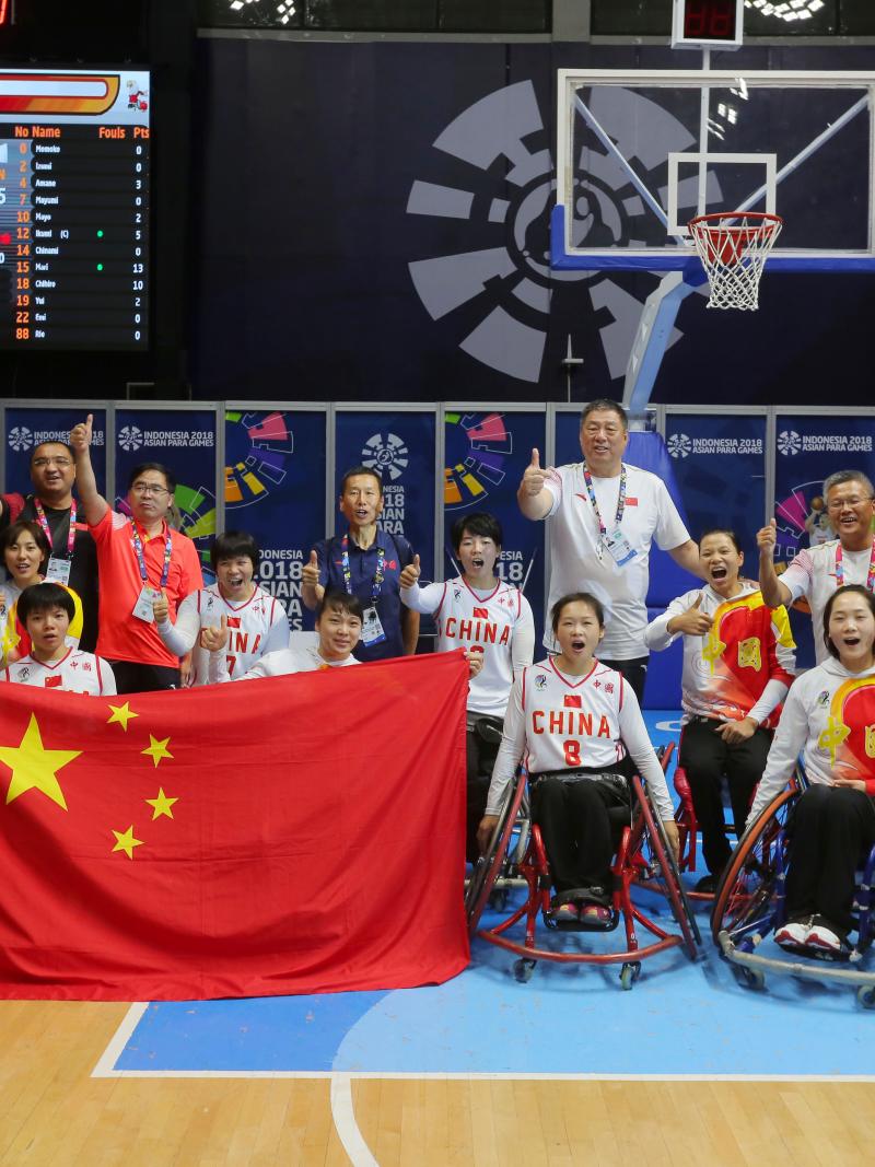 a female Chinese wheelchair basketballer shields the ball from another player