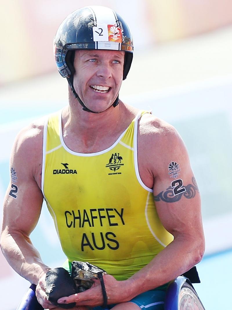 male Para triathlete Bill Chaffey smiles after crossing the finish line in his wheelchair