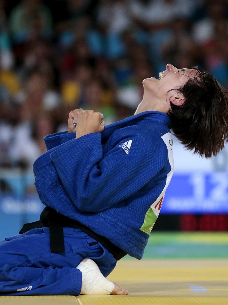 female judoka Sandrine Martinet sinks to her knees and clenches her fists after winning