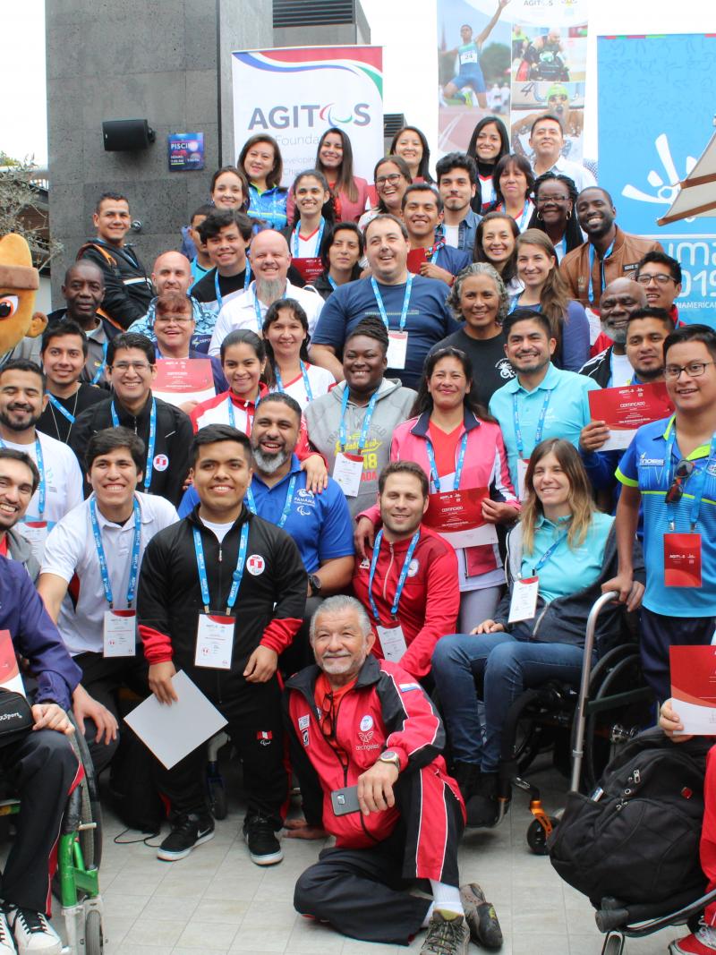a group of people and the Lima 2019 mascot smile for a photo