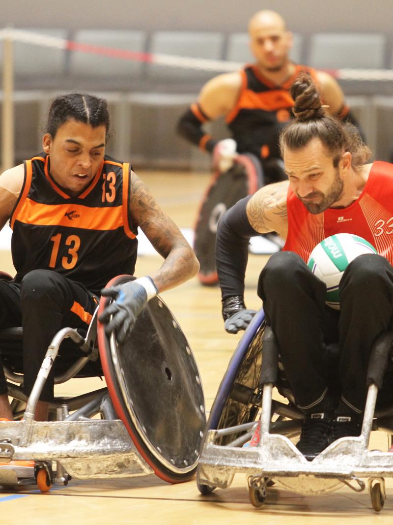 Two male wheelchair rugby players collide with their wheelchairs