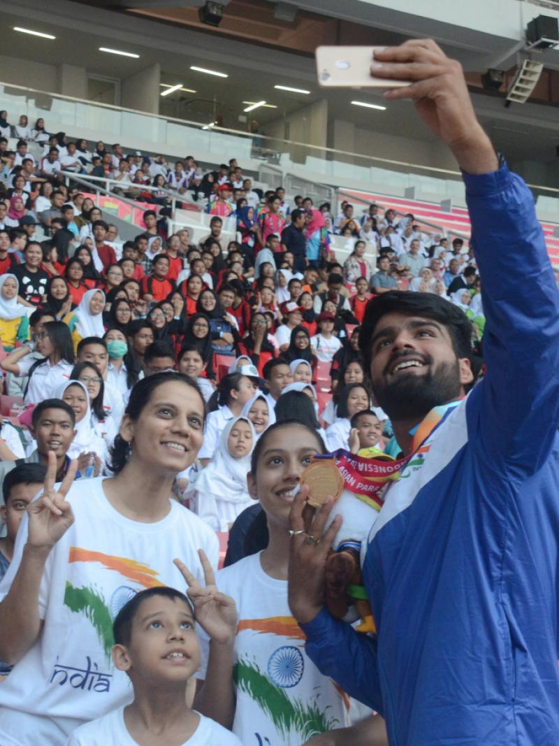 Man with a medal taking pictures with fans on the stands in a stadium