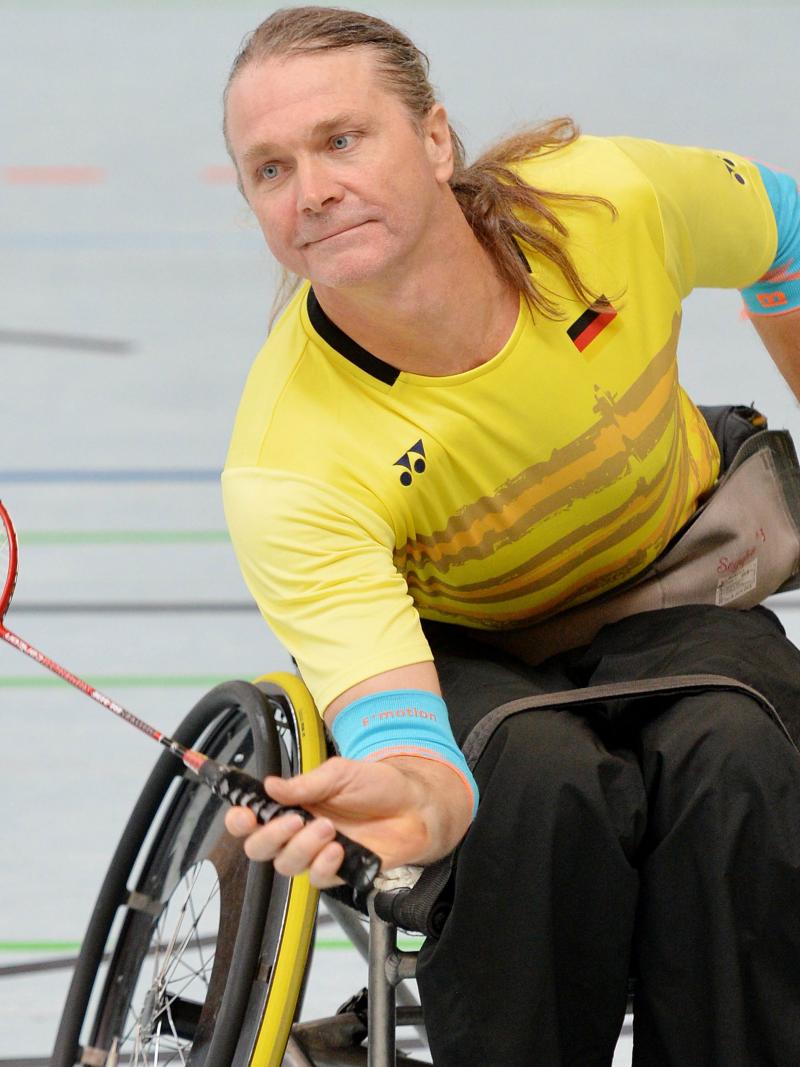 male Para badminton player Thomas Wandschneider reaches down to hit a forehand