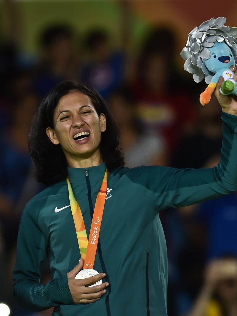 female judoka Lucia Araujo smiles on the podium holding up a mascot 