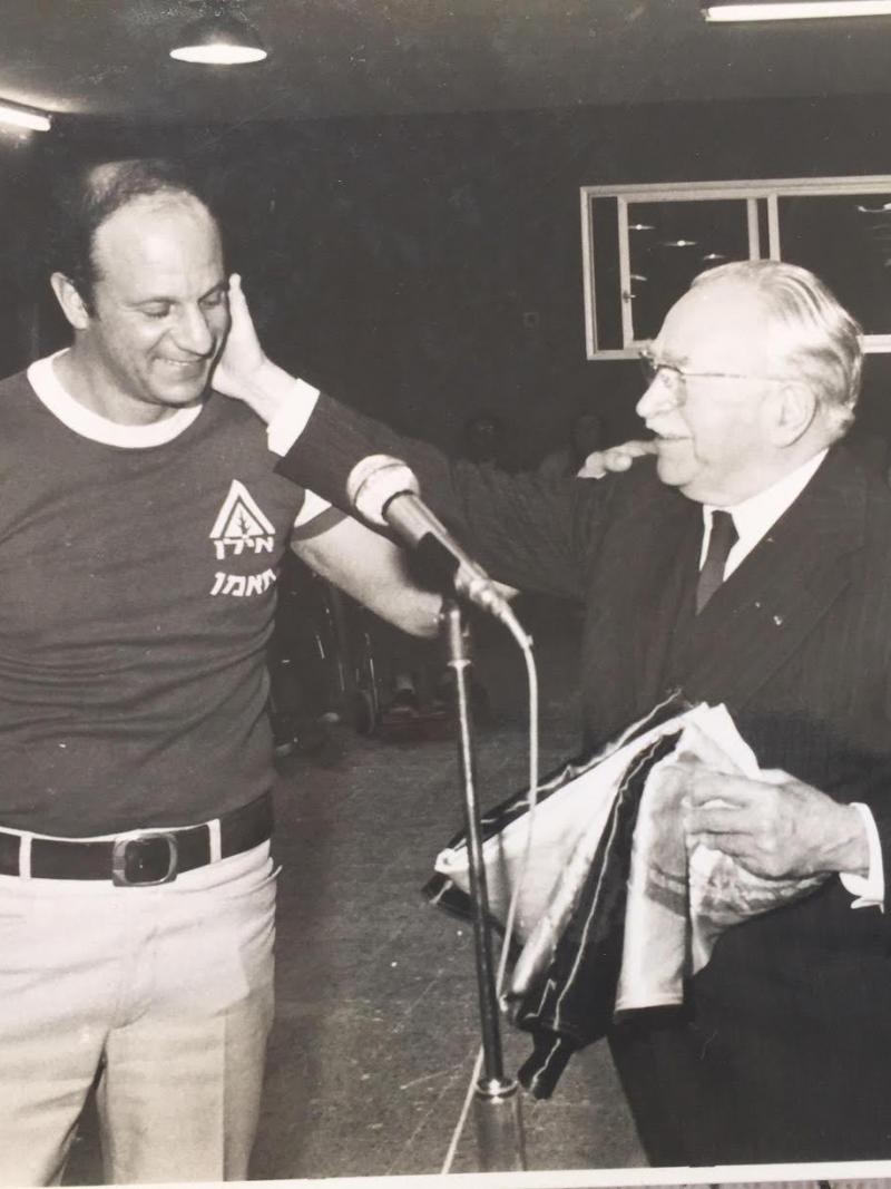 Reuven Heller puts his arm on the shoulder of Sir Ludwig Guttman who is touching his face