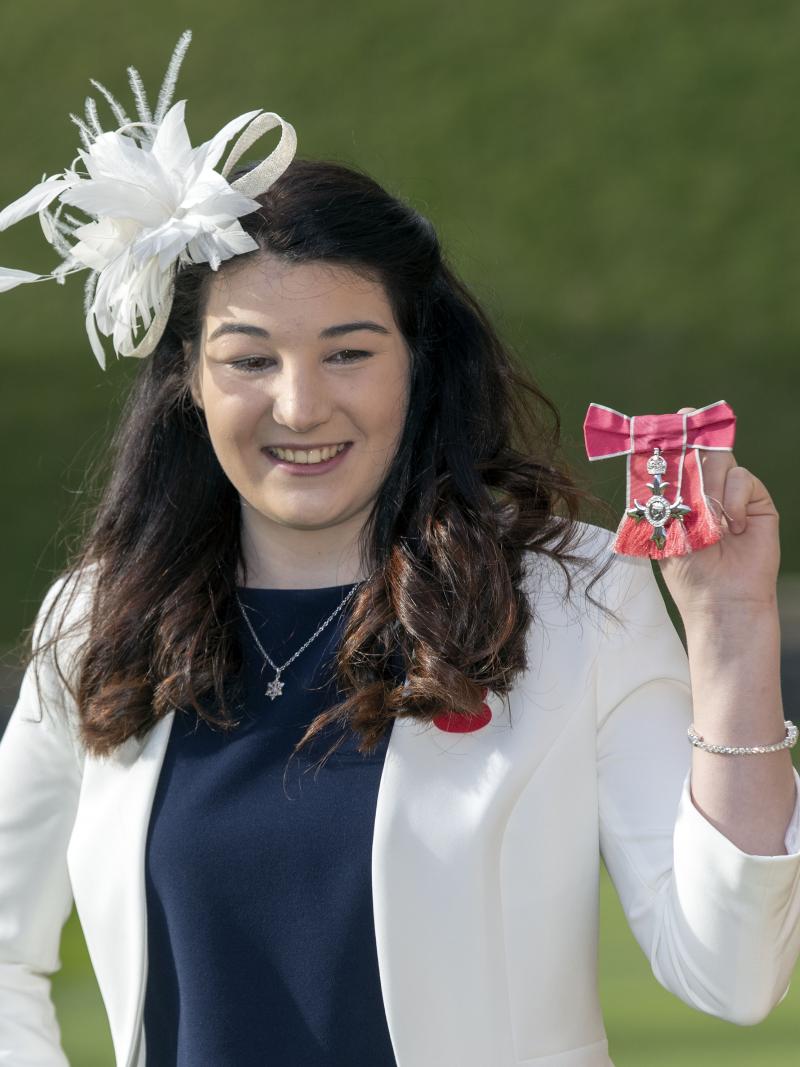 Female Para alpine skier Menna Fitzpatrick holding up her MBE medal