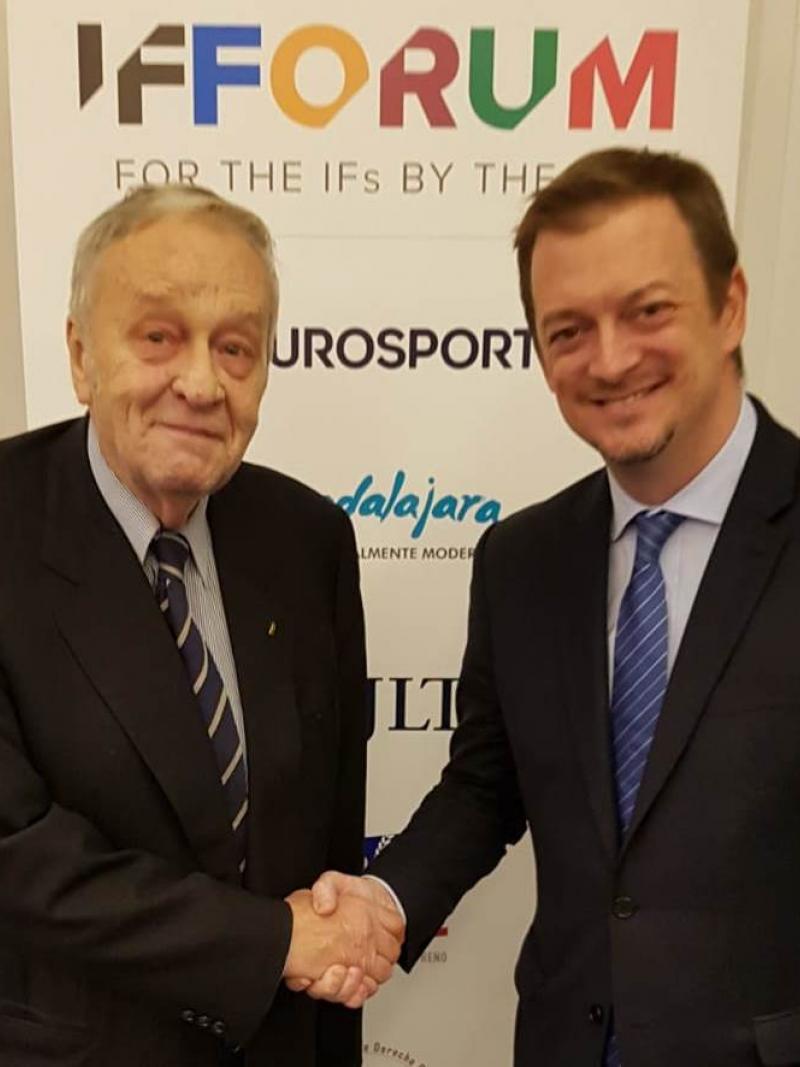 Two men shaking hands and smiling to the camera