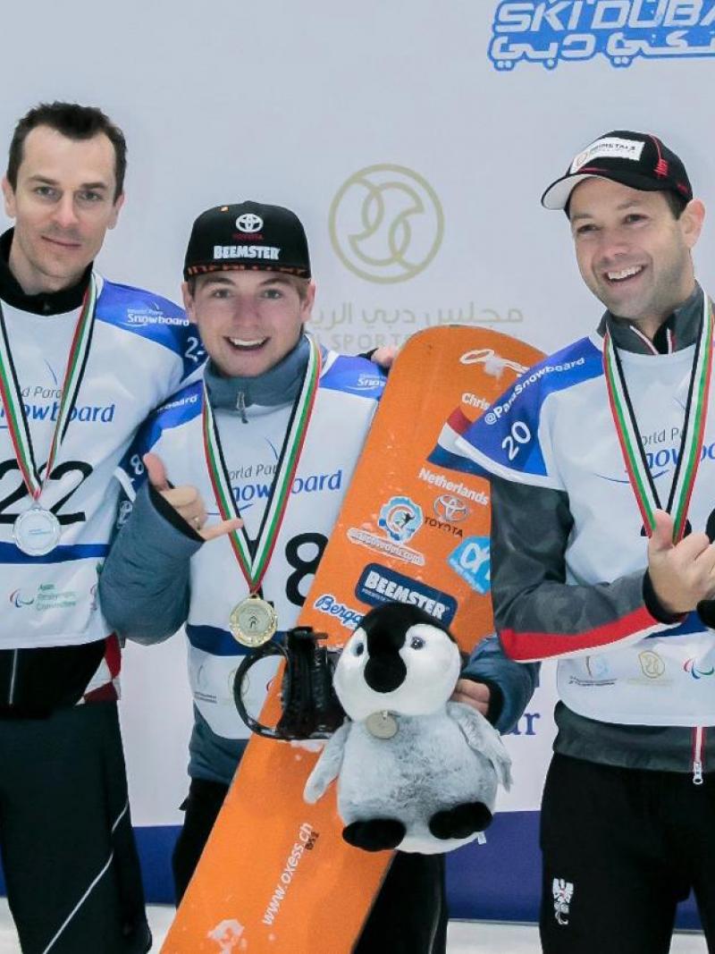 Three men with helmets in an indoor snowboard track