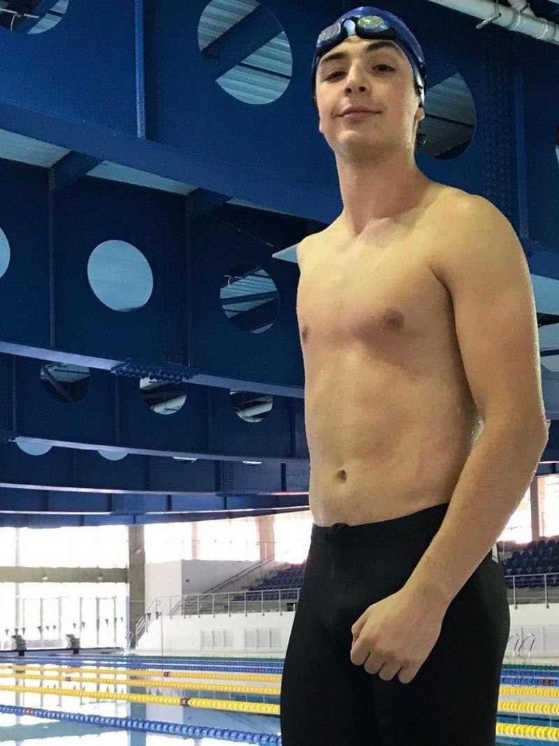A young athlete withou one arm standing in front of a swimming pool