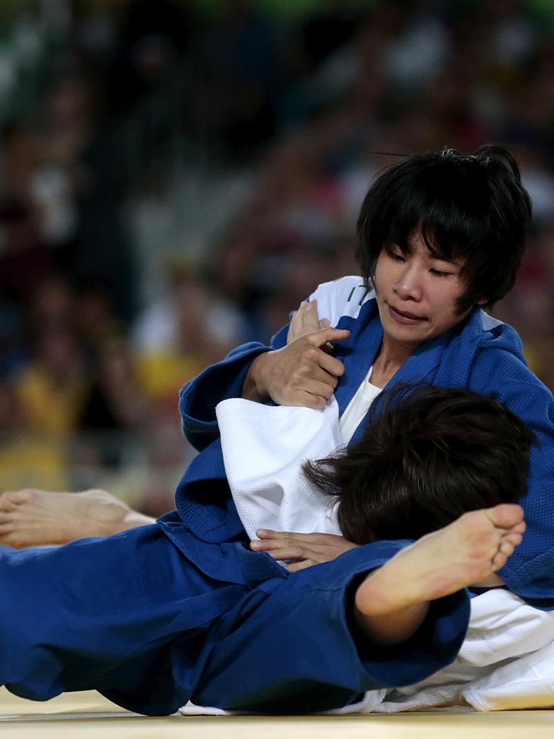 female judoka Li Liqing wrestles another female judoka to the ground on the mat
