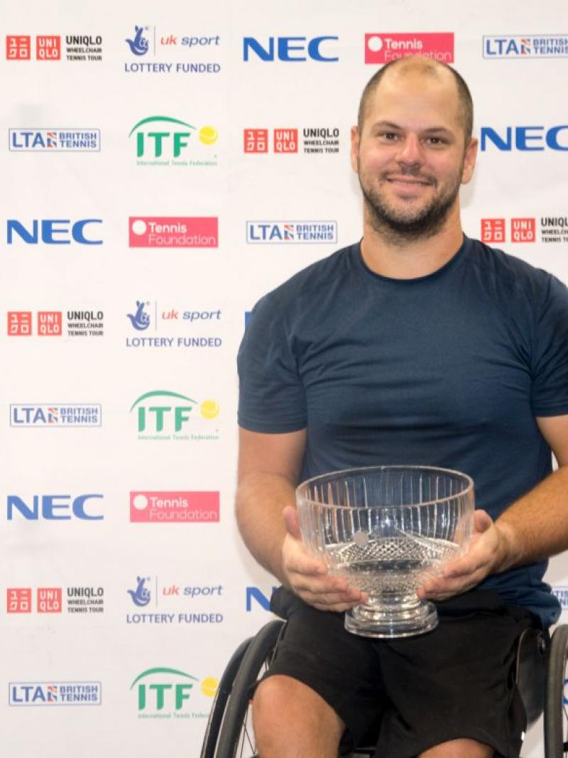 male wheelchair tennis player Stefan Olsson smiling and holding a crystal trophy