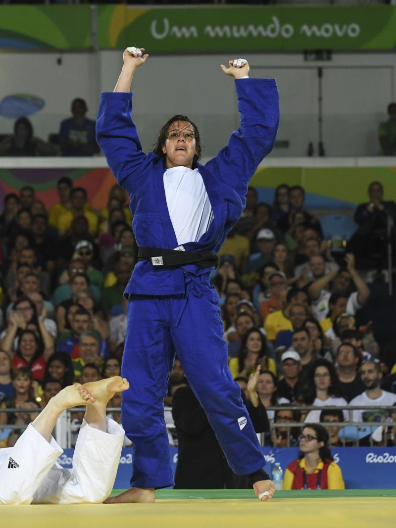 female judoka Naomi Soazo raises her arms straight up in the air in celebration