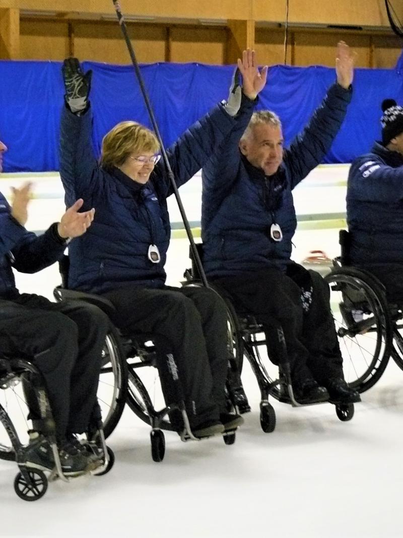 Four Estonian wheelchair curling athletes celebrate a shot on the ice sheet