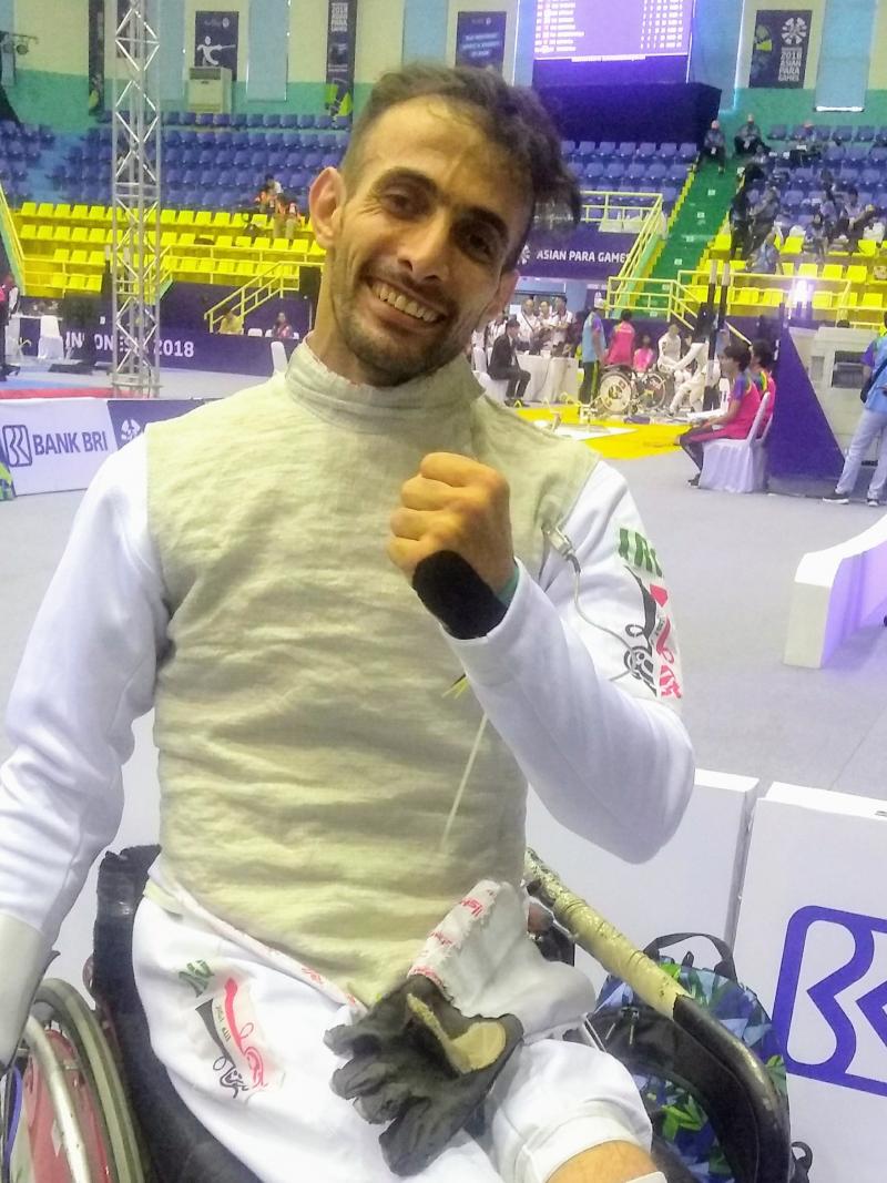 A man in a wheelchair wearing a fencing uniform