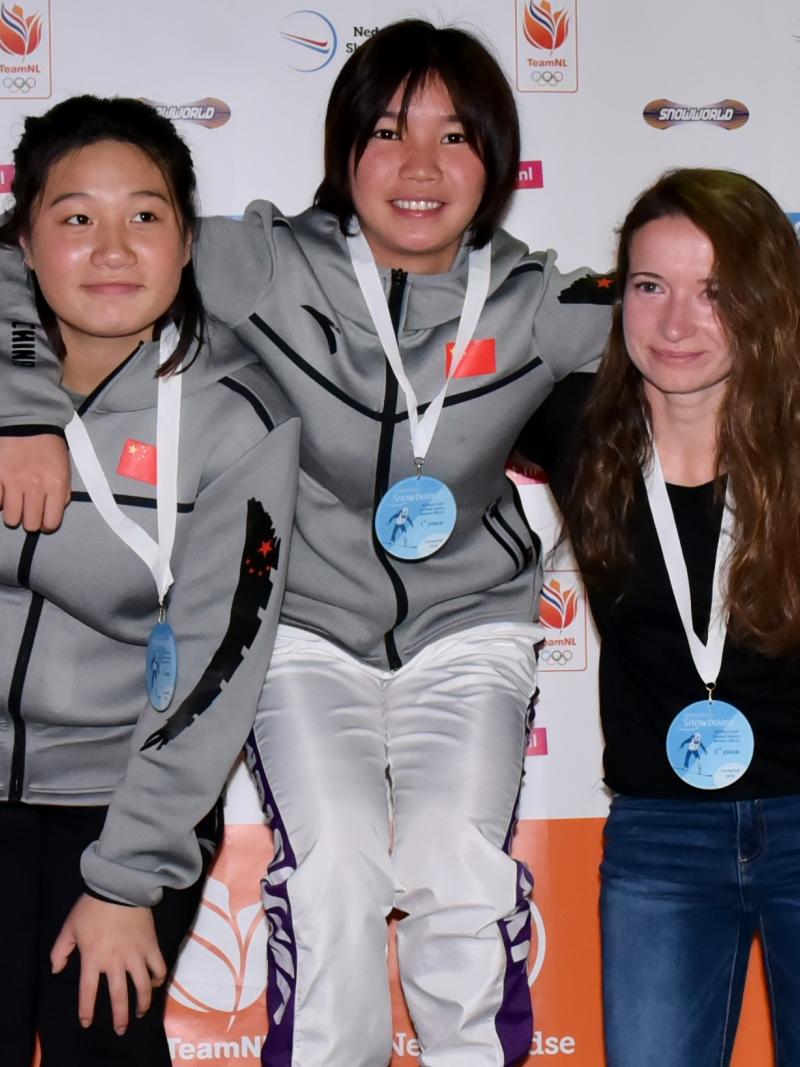 three female snowboarders standing on the podium with their arms around eachother