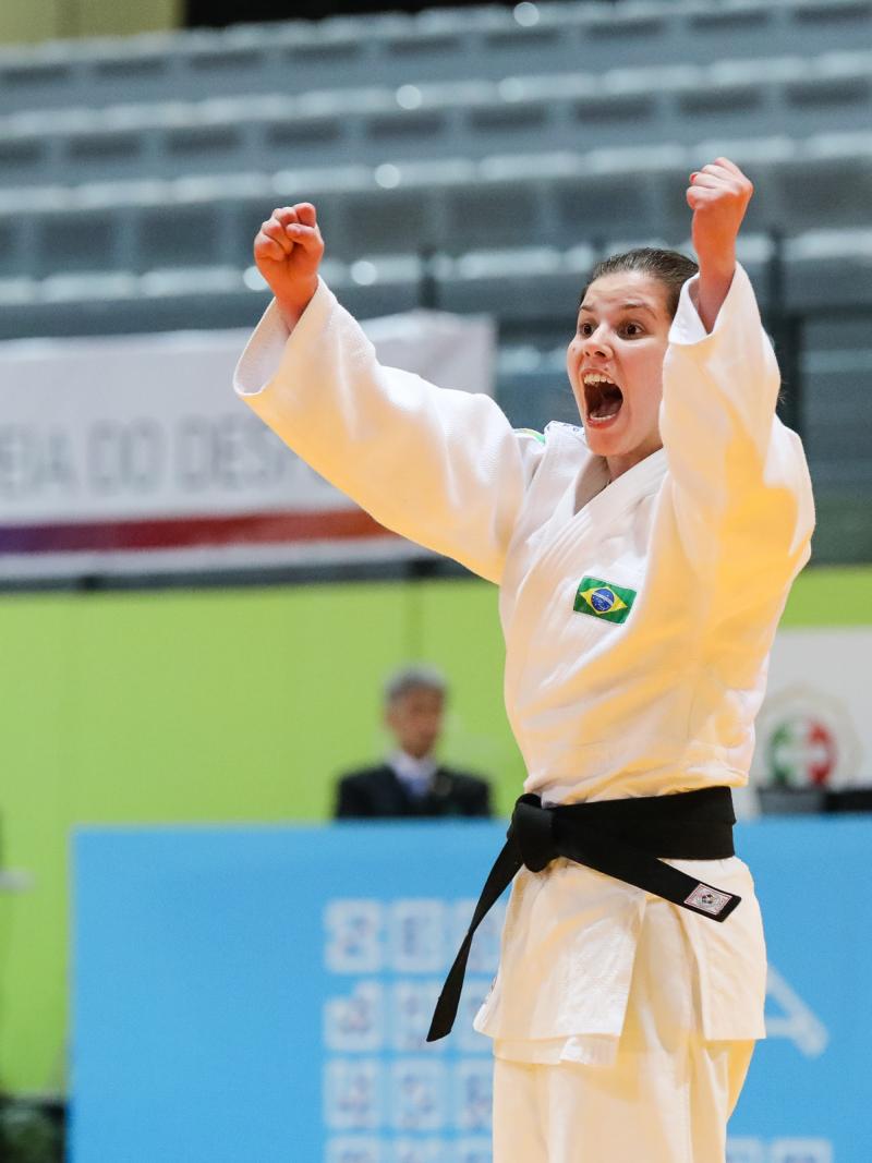 female judoka Alana Maldonado raises her arms to the ceiling in victory