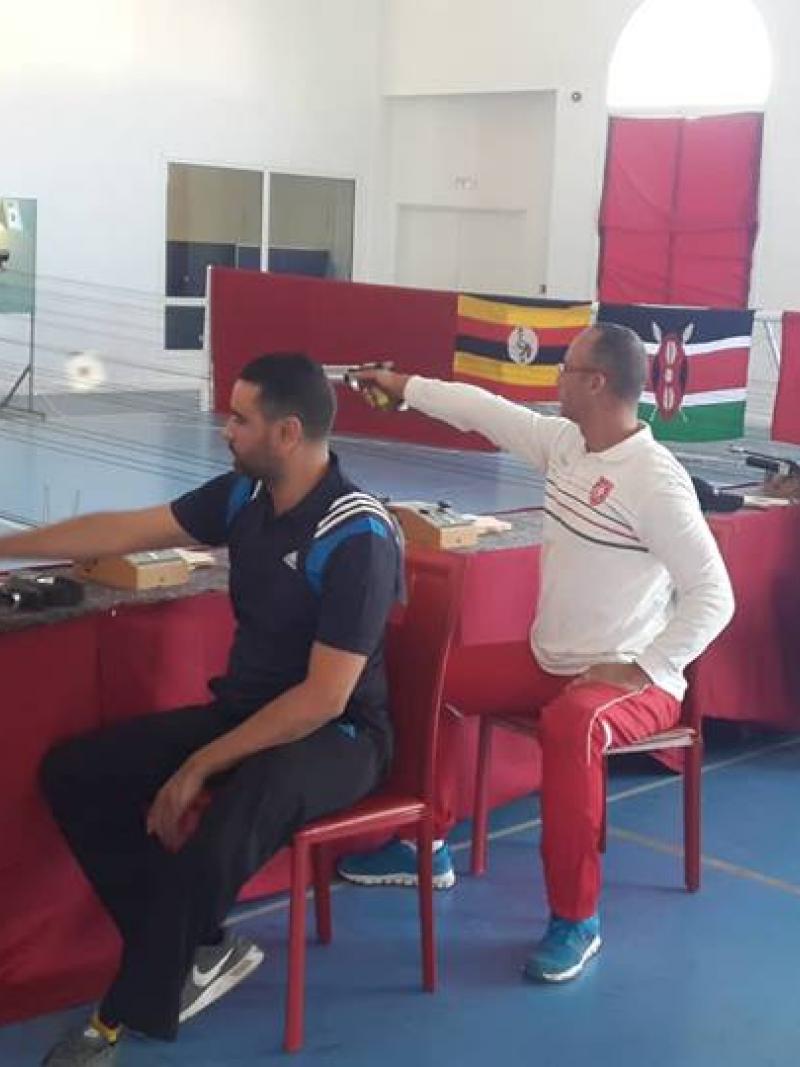 Five men competing in an indoor shooting event