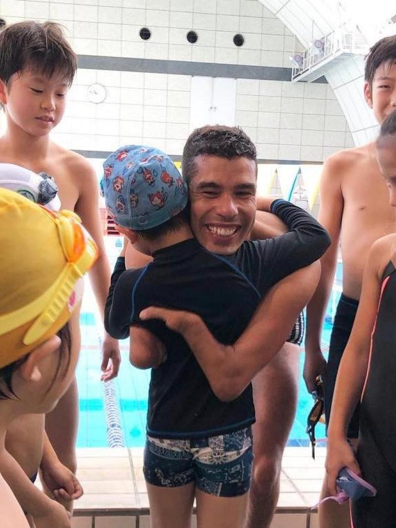 A man hugging a child in the middle of a group of children