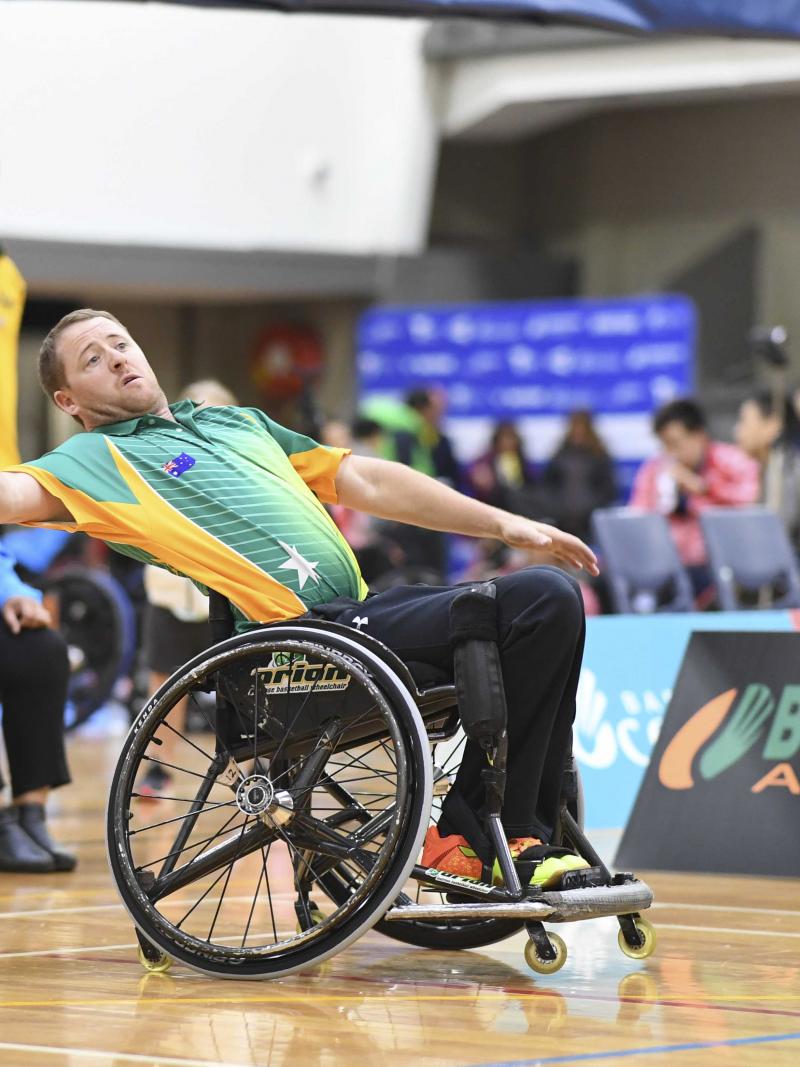Male Australian badminton player in a wheelchair attempts to hit the birdie in the air