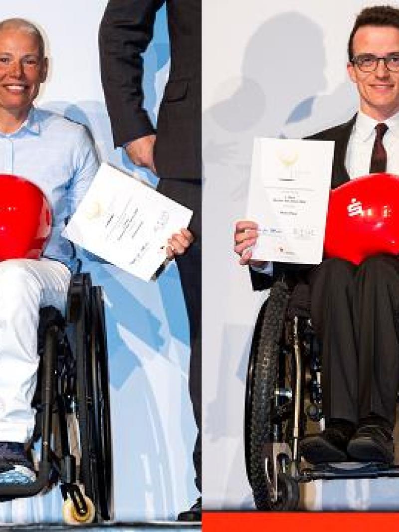 A woman and a man in wheelchairs holding a trophy and a certificate
