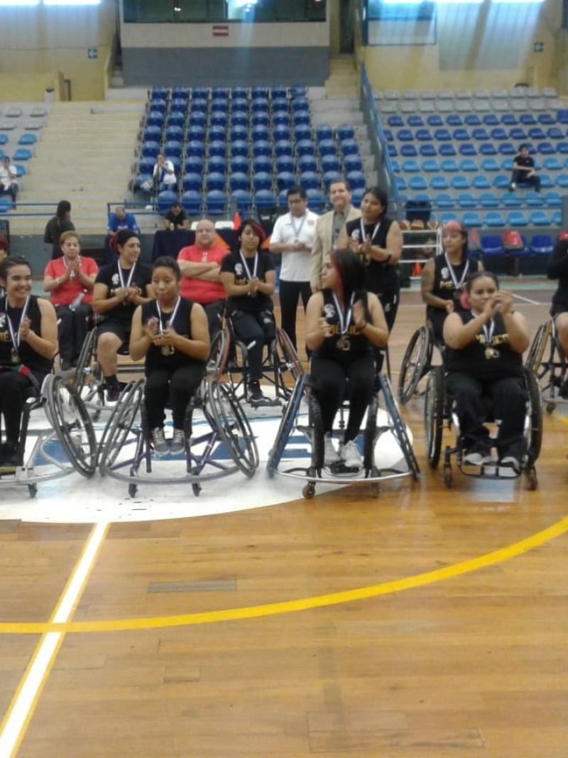 Female Mexican wheelchair basketball players pose after a victory