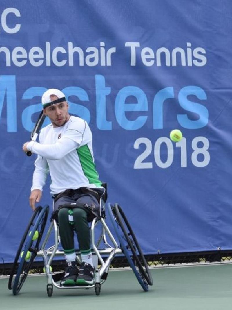 Male in wheelchair hits a tennis ball
