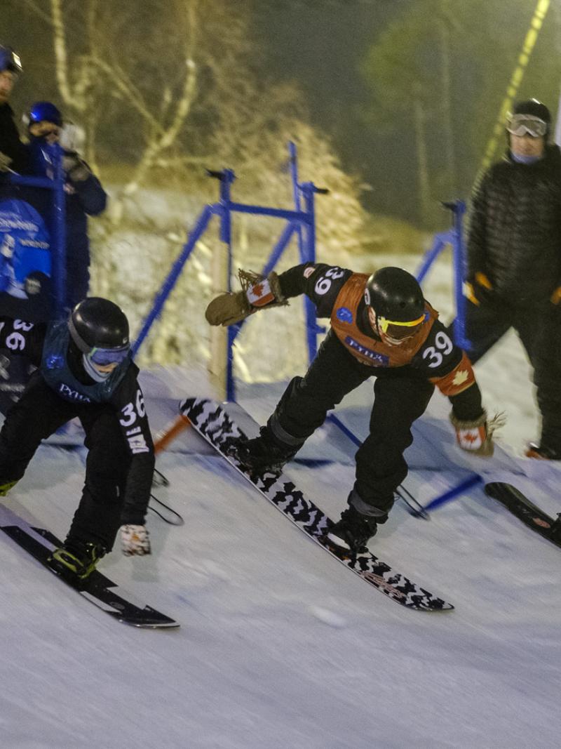 Four male snowboarders at the start gate for snowboard-cross