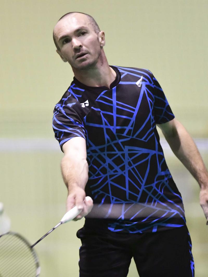 male Para badminton player Corrie Keith Robinson standing and playing a forehand shot