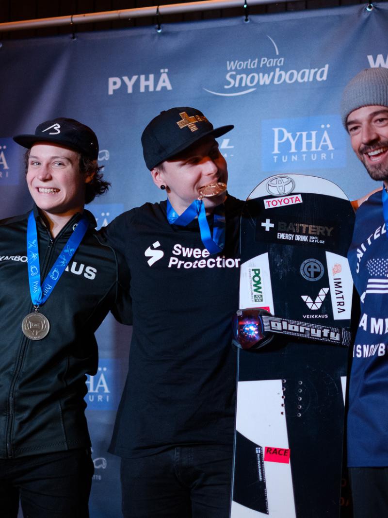 Three male snowboarders pose together with their medals