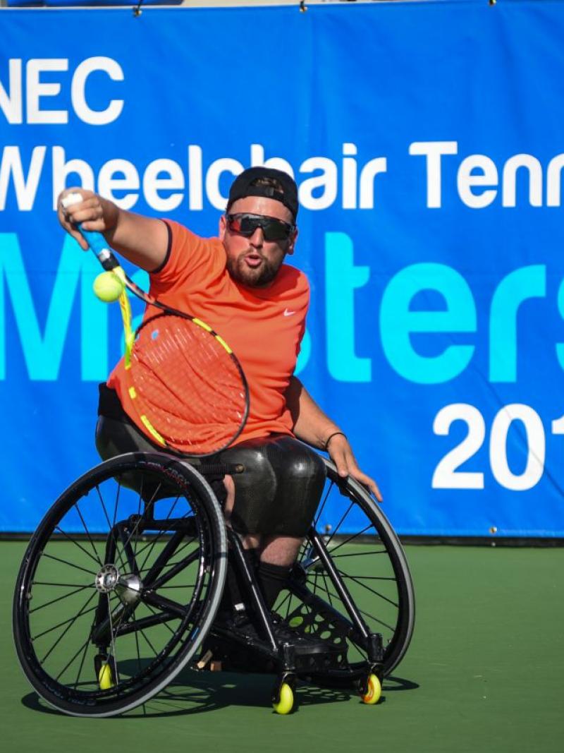 male wheelchair tennis player Dylan Alcott plays a backhand on a hard court