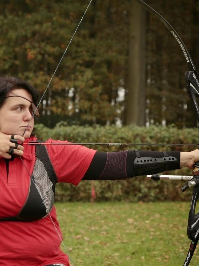 female Para archer Milena Olszewska draws back an arrow and prepares to shoot