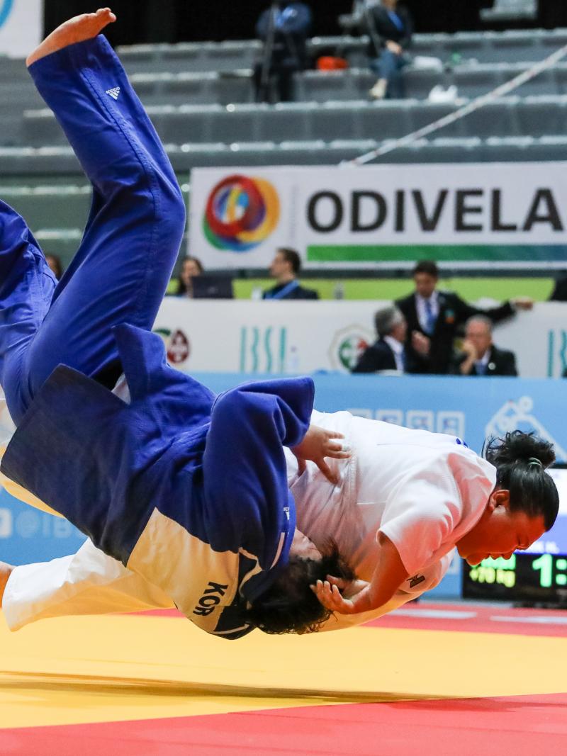 Judokas holding each other while falling onto the tatami