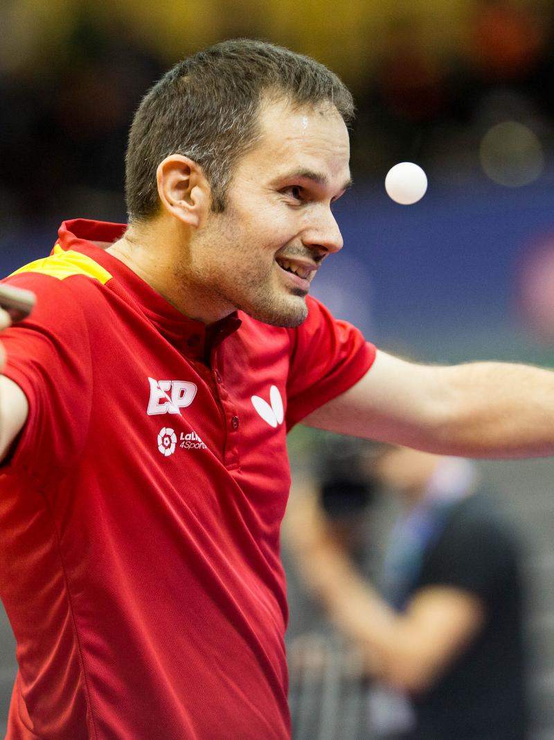 male Para table tennis player Jordi Morales raises his arms at the table 