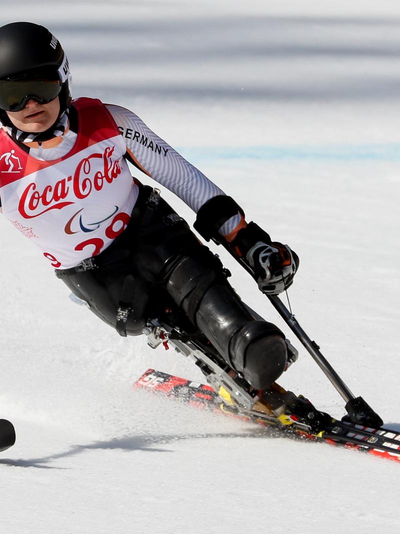 female Para alpine skier Anna-Lena Forster leans to the left as she skis down the slope