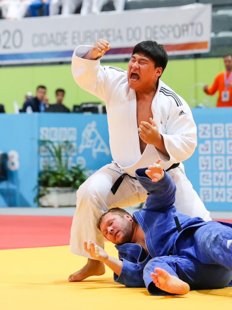 a male South Korean judoka punches the air after throwing his opponent to the ground