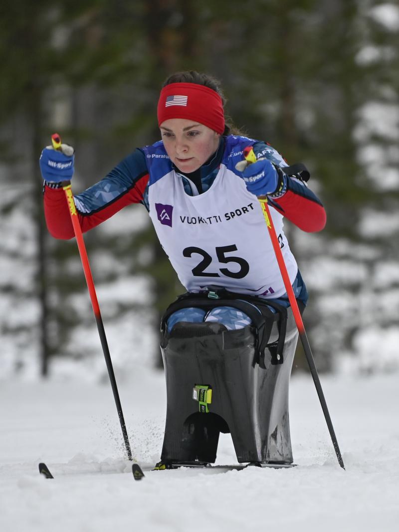 female Para Nordic sit skier Kendall Gretsch pushing through the snow