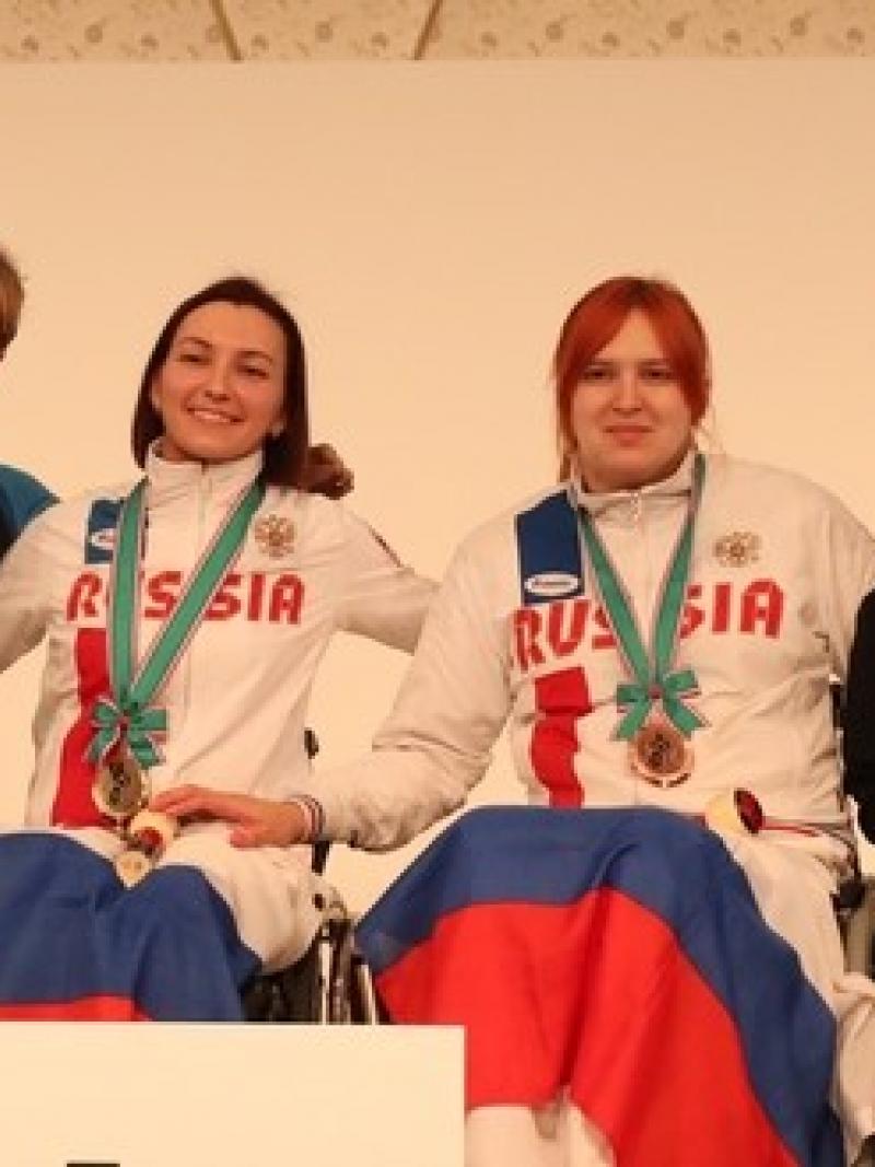 female wheelchair fencers Ludmila Vasileva and Beatrice Vio hugging on the podium