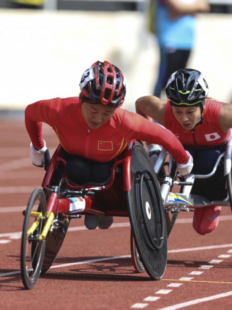 female wheelchair racer Hongzhuan Zhou rolls her wheels to stay ahead of a Japanese athlete