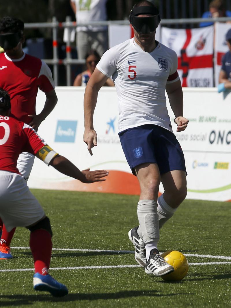 male blind footballer Dan English dribbles the ball past an opposition player