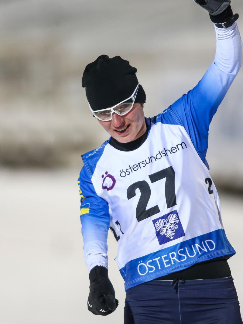 female Para biahthlete Oleksandra Kononova raises her fist in triumph as she crosses the finish line