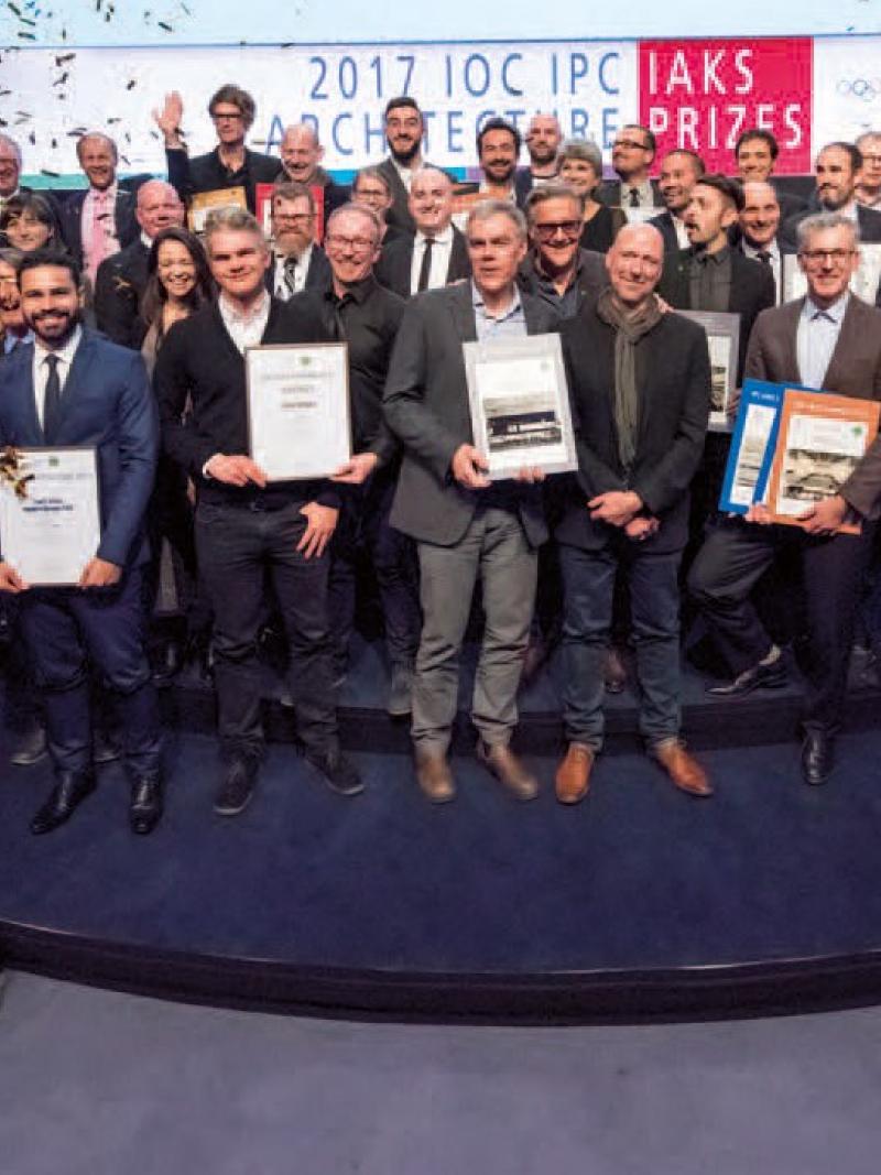 a group of male and female architects standing holding certificates and being sprayed with confetti
