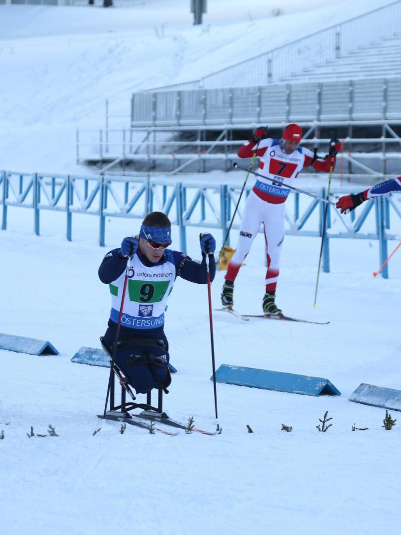 A group sitting and standing skiers competing in a Para biathlon race