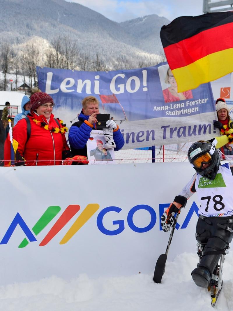 A sit-skier celebreating in front of a group of five people
