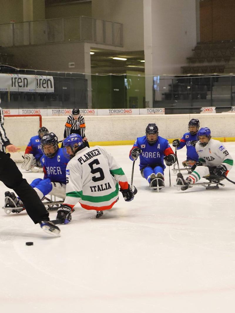 Two referees, three Italian and five South Korean Para ice hockey players on ice