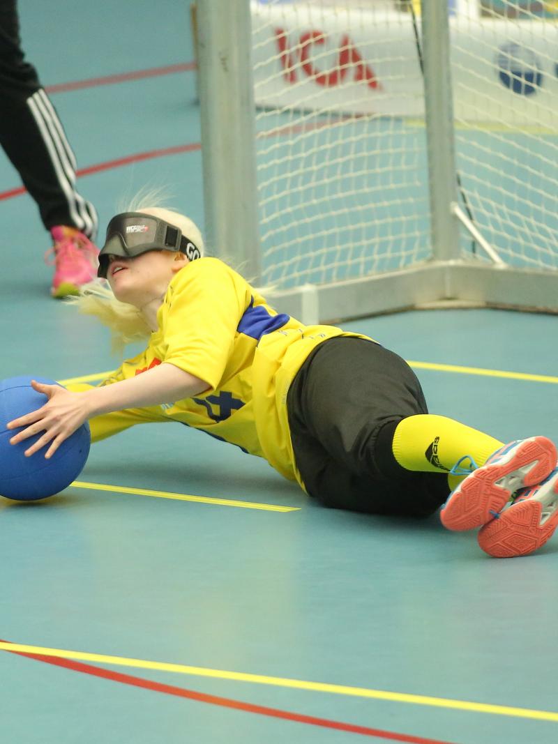 a female goalball player makes a save on the ground
