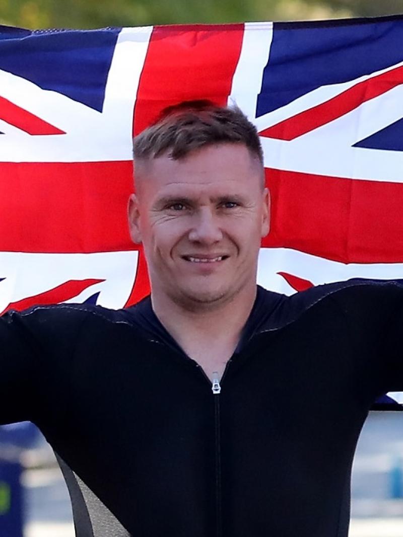 male marathon wheelchair racer David Weir holding up the British flag and smiling
